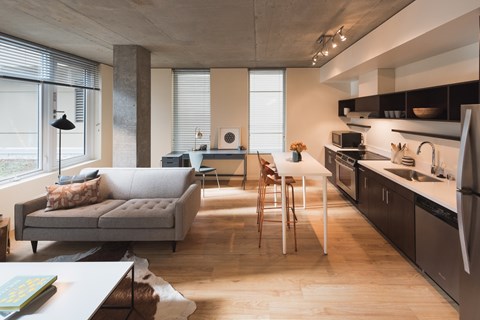 A modern living room with a grey couch and wooden floors.